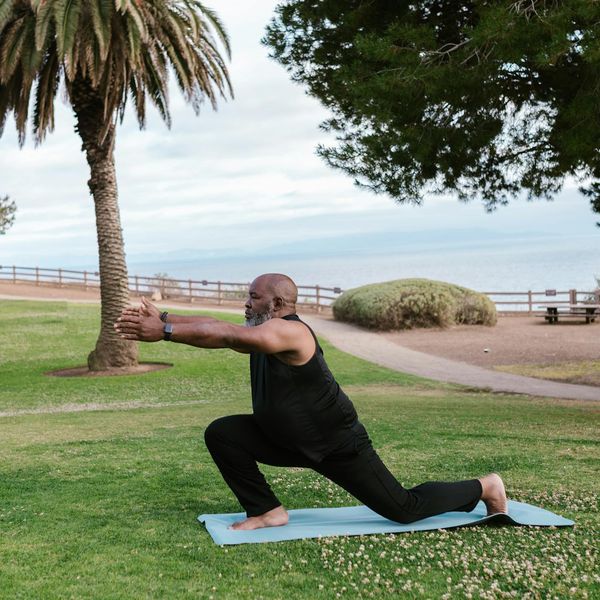 A person stretching gently on a yoga mat with mint green light.